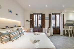 A hotel room with a bed, a desk, and a chair. There are towels on the bed and a coat rack in the corner. - Studio 73 – The Charm of La Marina (Cagliari)