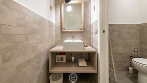 A modern bathroom with a rectangular sink, a mirror above it, and a toilet to the right.
