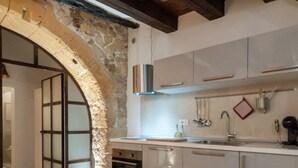 A modern kitchen with stone walls, a built-in oven, and stainless steel appliances.