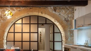 A kitchen with stone walls, an arched doorway, and modern cabinetry.