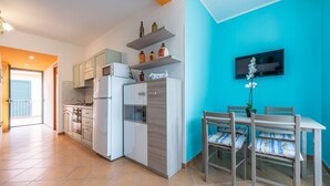 Eine moderne Küche mit weißen Geräten, einem Essbereich mit Tisch und Stühlen sowie einer Wand in Blautönen.