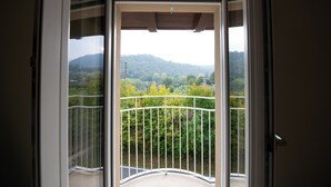 Een balkon met uitzicht op een groen landschap en heuvels.