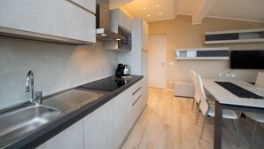 Een moderne keuken met een inbouwoven, een spoelbak en een eethoek met een tafel en stoelen.
