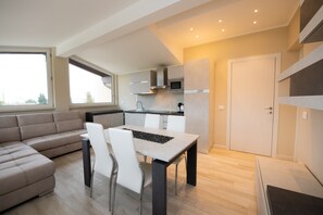 A modern apartment with a dining area, kitchen, and living space. - Le Nuove Rondini (Roe Volciano)