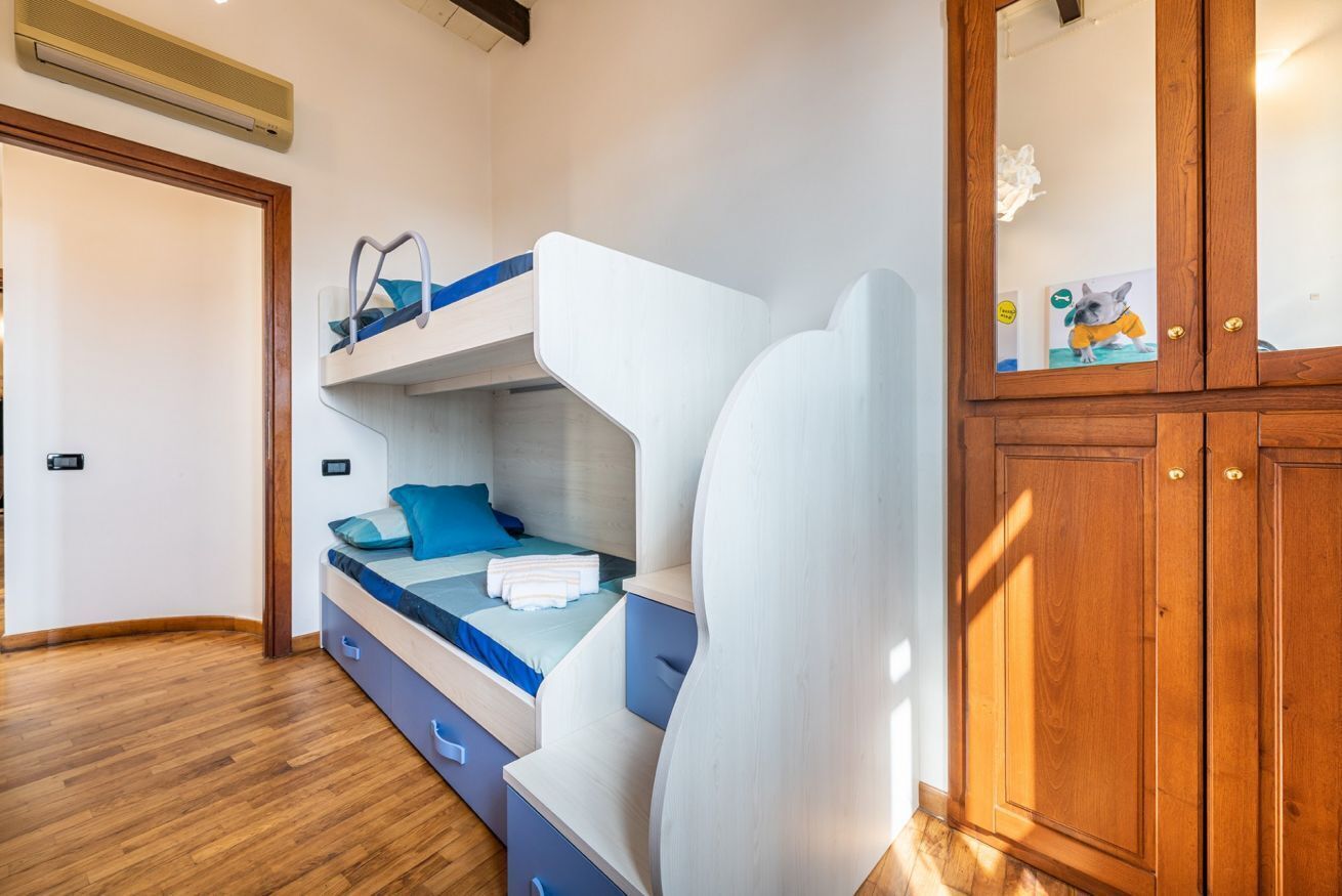 Ein Stockbett mit blauer Kopfteil, ein Holzschrank und eine kleine Ablage mit einer Hundefigur.
