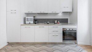 Eine moderne Küche mit weißen Schränken, einem eingebauten Backofen und einer Mikrowelle.