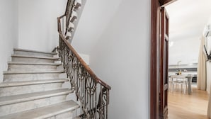 Eine Treppe mit Holzbalken und Marmorstufen, die zu einem Raum mit Essbereich führt.