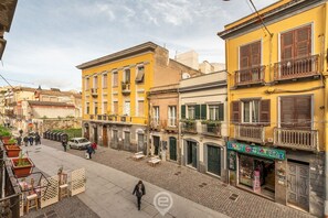 Vista de una calle con edificios, una persona caminando y una tienda con un letrero.