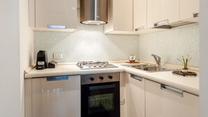 A modern kitchen with a gas stove, oven, and built-in dishwasher. - Piazza Yenne Apartment (Cagliari)