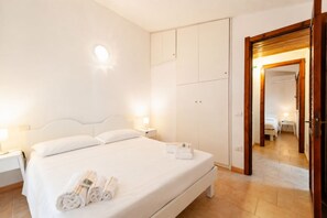 A hotel room with a bed, bedside tables, a wardrobe, and a mirror.