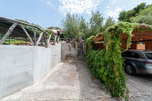 Un estrecho sendero de hormigón que lleva a una zona cubierta con estructura de techo metálico.