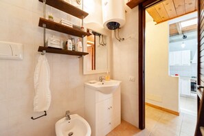 A bathroom with a sink, mirror, towel rack, and shelves with toiletries.