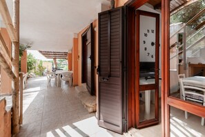 A covered outdoor area with a wooden door, a white table, and chairs.