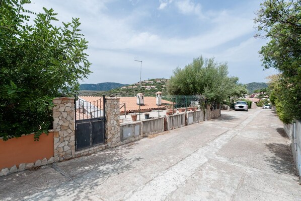 A residential street with houses, a stone wall, and a clear view of the surrounding hills.