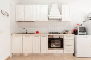 Una cocina moderna con armarios blancos, estufa a gas, horno y microondas.