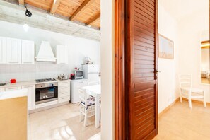 A kitchen with white cabinets, a stove, and a dining area with a white table and chairs.