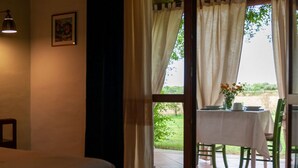 A room with a bed, a bedside table, a lamp, and a window with curtains.