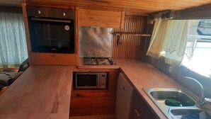 A compact kitchen with wooden cabinets, a microwave, a stove, and a sink. - Rooftop authentic close to metro (ÜMRANIYE)