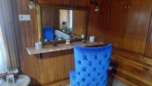 A room with a wooden cabinet, a blue upholstered chair, a small table with a lace doily, and a mirror on the wall. - Rooftop authentic close to metro (ÜMRANIYE)