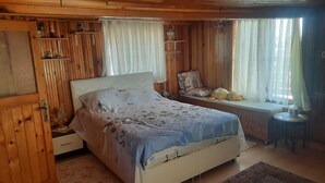 A wooden-paneled bedroom with a bed, a small table, and a window with curtains. - Rooftop authentic close to metro (ÜMRANIYE)