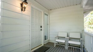 A porch with a white door, a bench, and a wall-mounted light fixture. - Located in the Luxurious Pine Manor Estates! (Carbondale)