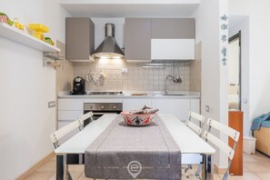 Cozinha moderna com armários brancos, fogão a gás e uma mesa de jantar com cadeiras.