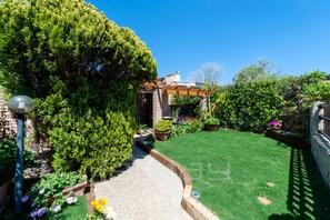 A well-maintained garden with a lawn, potted plants, and a pergola.