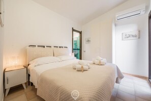 Ein Hotelzimmer mit einem großen Bett, einem Nachttisch mit Lampe, einer Wand-Klimaanlage und einem gerahmten Bild an der Wand.