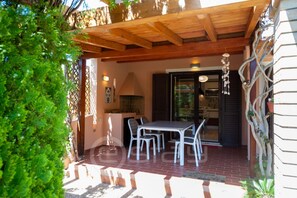 Eine überdachte Terrasse mit Tisch und Stühlen, einer Holzbalkendecke und Blick ins Haus.