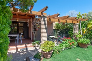 Ein möblierter Patio-Bereich mit Pergola und Pflanzen in Töpfen.