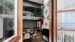 A modern kitchen with a dining area, a glass balustrade, and a decorative wall panel. - KyS Castello - Suite Lamarmora (Cagliari)
