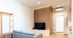 Una sala de estar moderna con un televisor de pantalla plana, un sofá azul y una pared de acento de madera.