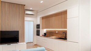 Une cuisine moderne avec des meubles blancs, un plan de travail en bois et un four encastré.