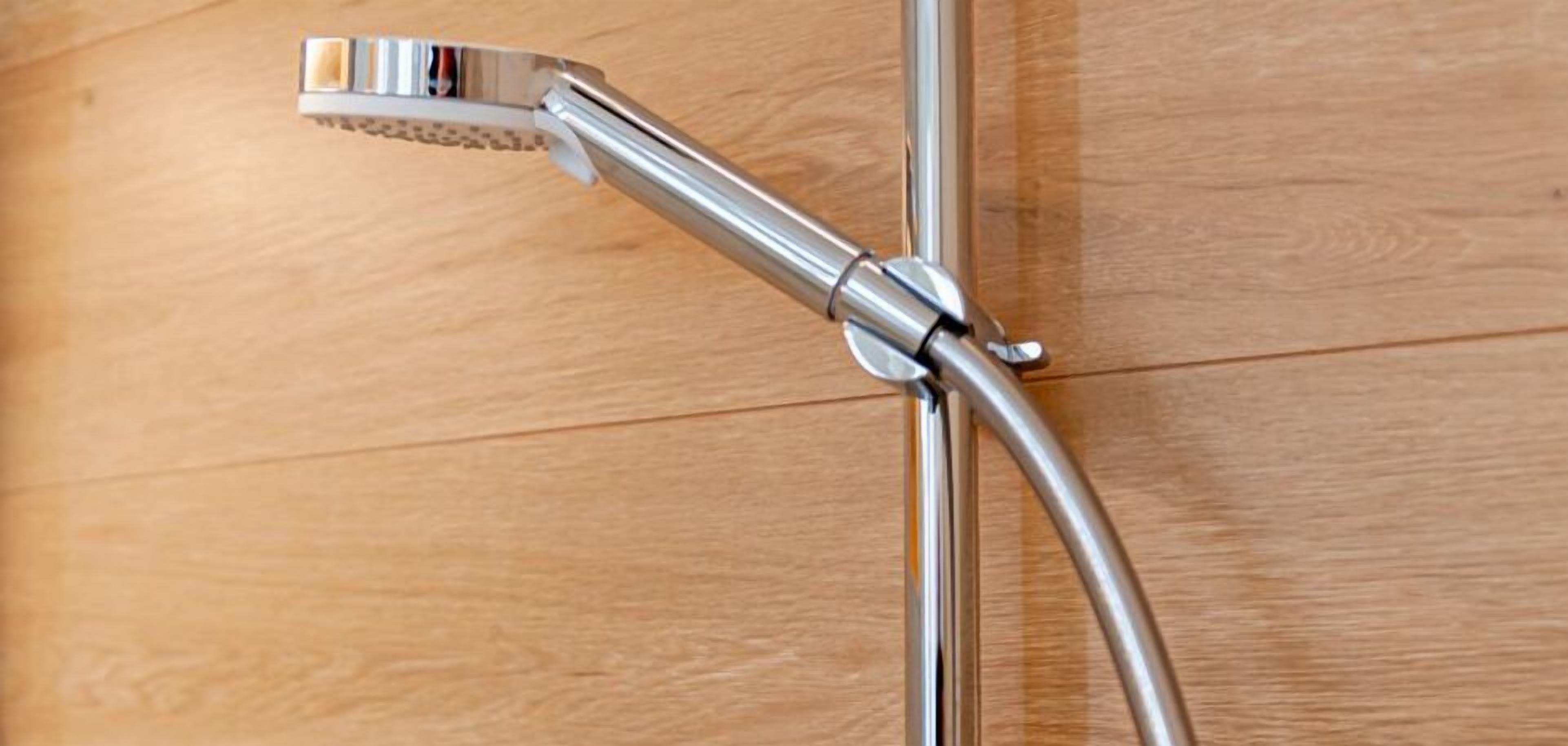 A showerhead attached to a metal pipe, likely part of a bathroom's plumbing system.
