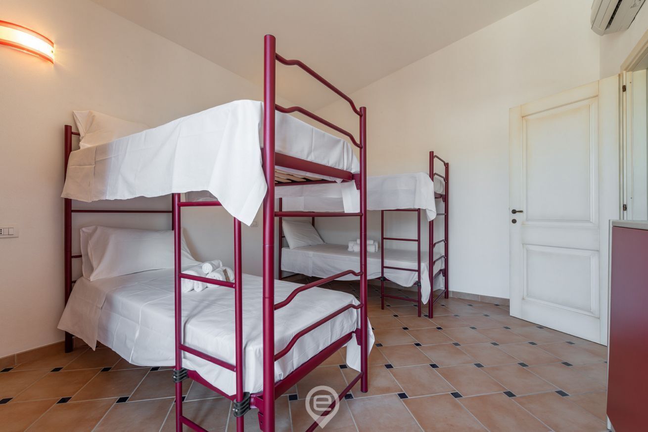 A room with bunk beds, a door, and a tiled floor.