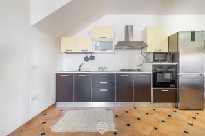 A modern kitchen with dark cabinets, a stainless steel refrigerator, a microwave, and an oven.