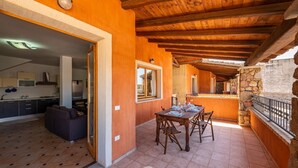 A spacious living area with a wooden ceiling, a dining table set for four, and a stone wall.
