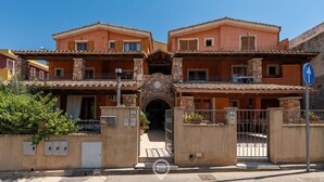 A traditional Mediterranean-style building with a central archway, stone pillars, and a gated entrance.