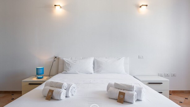 A hotel room with a large bed, two bedside tables, and two wall-mounted lights.