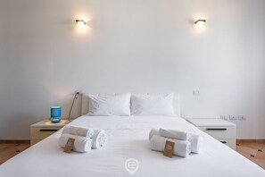 A hotel room with a large bed, two bedside tables, and two wall-mounted lights.