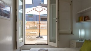 A bedroom with a bed, a nightstand, a lamp, and a view of an outdoor patio with a table and chairs. - A Gem in the City - Cagliari Centre (Cagliari)