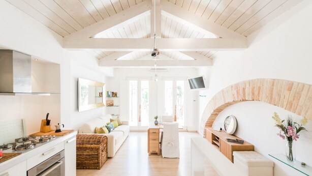 A spacious kitchen with modern appliances, a dining area with a white table and chairs, and a cozy seating area with a sofa and cushions. - A Gem in the City - Cagliari Centre (Cagliari)