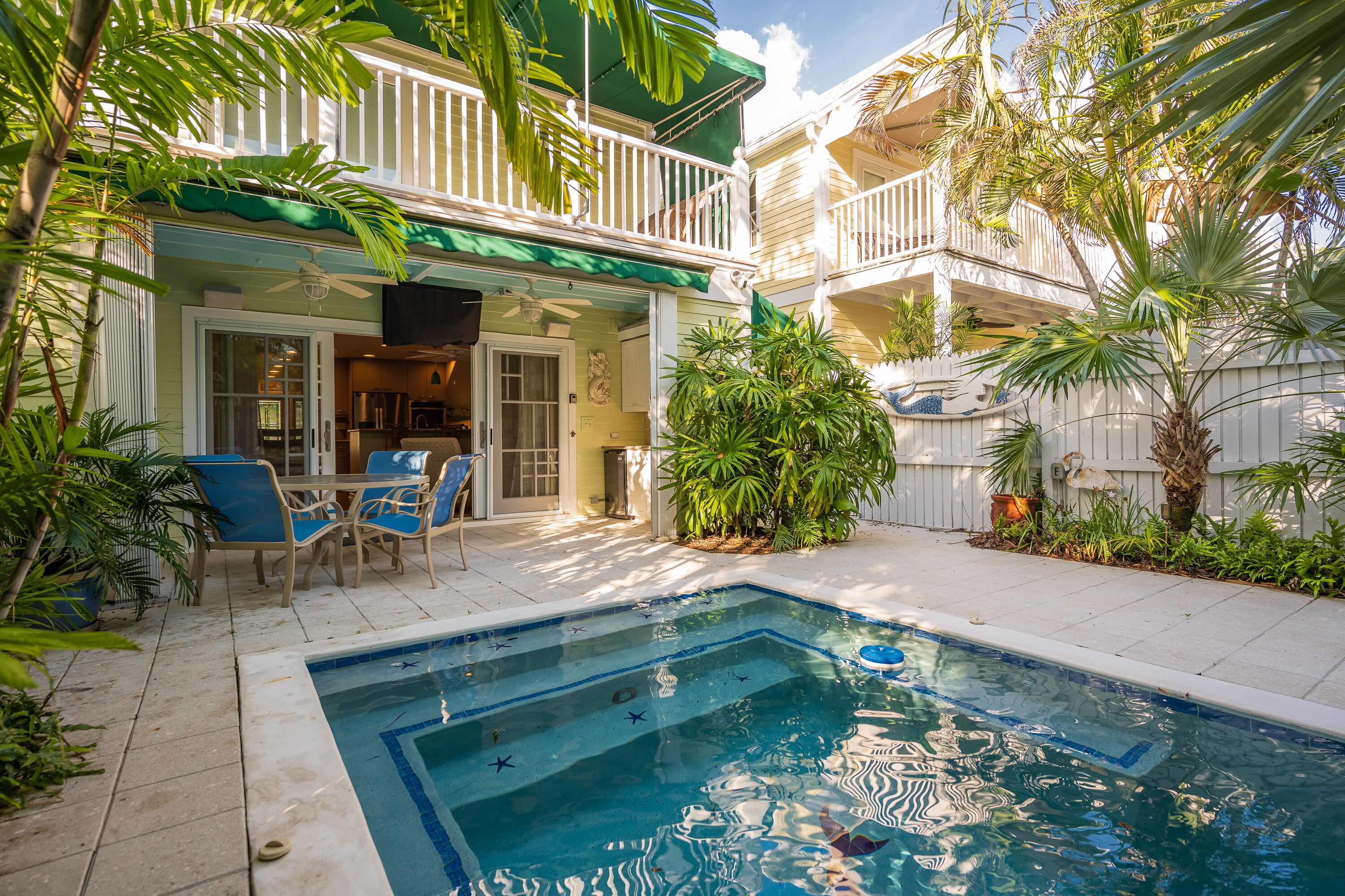 A pool area with a pool, lounge chairs, and a covered patio.