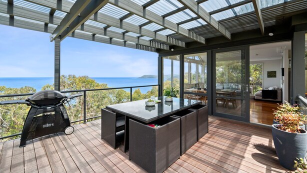 Un espacio al aire libre techado con una parrilla, una mesa de comedor y sillas, con vistas panorámicas.