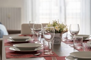 Una mesa de comedor dispuesta con platos, vasos y un florero con flores.