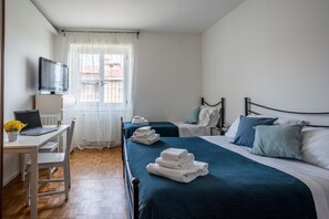 Een hotelkamer met een bed, een bureau met een laptop, een televisie en een raam met gordijnen.