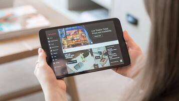 Une tablette affichant une interface de réservation de billets de théâtre en temps réel, avec des options pour les services à domicile, les événements locaux, les services en chambre et les offres spéciales sur les billets.