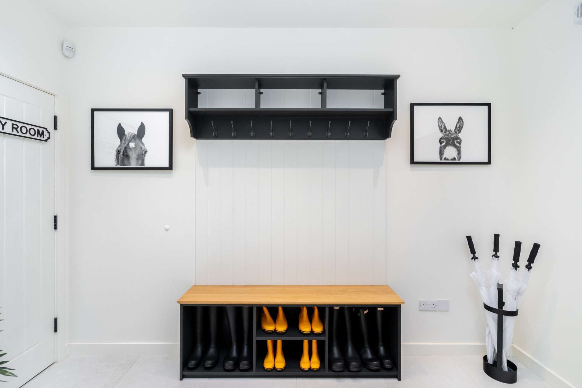 Ein Flur mit Kleiderhaken, einer Bank mit Stiefeln und zwei gerahmten Bildern an der Wand.