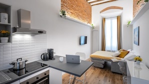 Une petite cuisine équipée d’une cuisinière, d’une machine à café et d’un ordinateur portable posé sur une table.