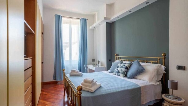 Um quarto com uma cama, uma escrivaninha e um guarda-roupa.